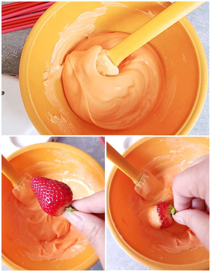 Dipping strawberries into orange meltables for carrot patch cupcakes.
